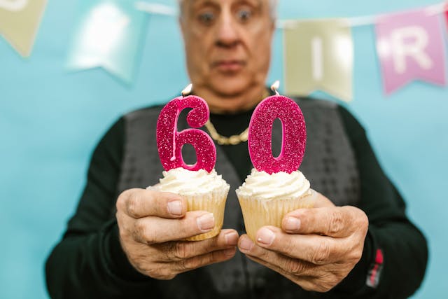 Man som håller i två cupcakes med siffrorna 6 och 0. Köp en unik 60 års present till pappa eller 60 års present till en man.